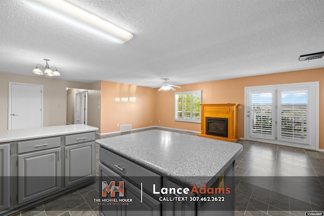 396 Williams Way, Glenrock, WY 82637 - kitchen featuring gray cabinetry, a center island, open floor plan, a textured ceiling, and a chandelier