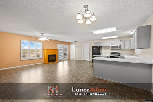 396 Williams Way, Glenrock, WY 82637 - kitchen with stainless steel appliances, a sink, a textured ceiling, a glass covered fireplace, and a peninsula