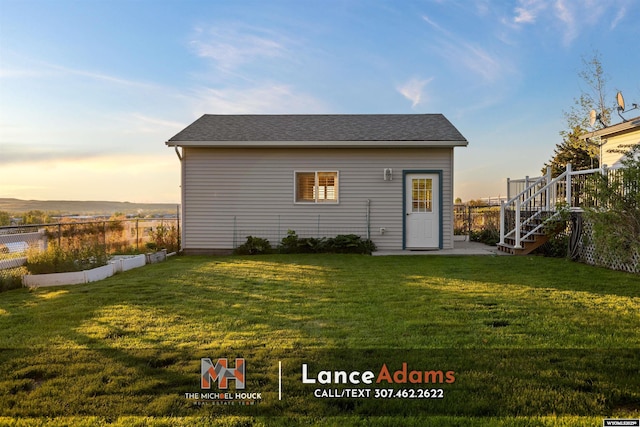 396 Williams Way, Glenrock, WY 82637 - back of house at dusk featuring stairway and a shingled roof