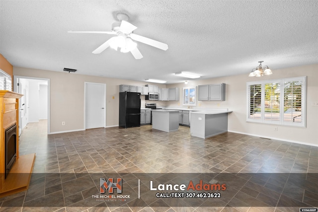 396 Williams Way, Glenrock, WY 82637 - kitchen with freestanding refrigerator, stainless steel microwave, gray cabinetry, a textured ceiling, and a chandelier
