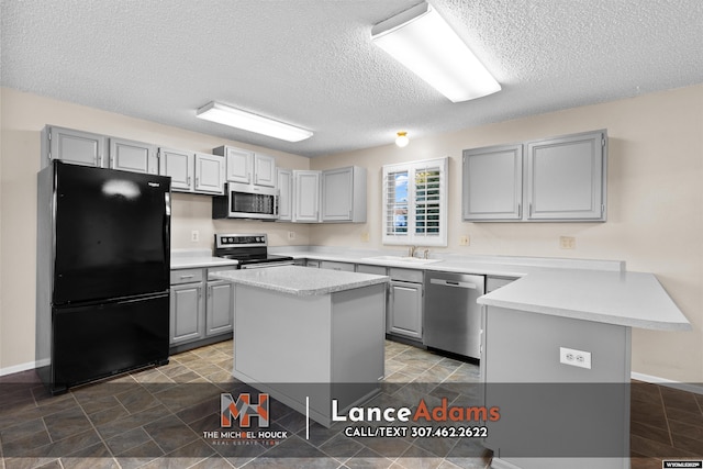 396 Williams Way, Glenrock, WY 82637 - kitchen with appliances with stainless steel finishes, gray cabinets, a peninsula, a sink, and a textured ceiling