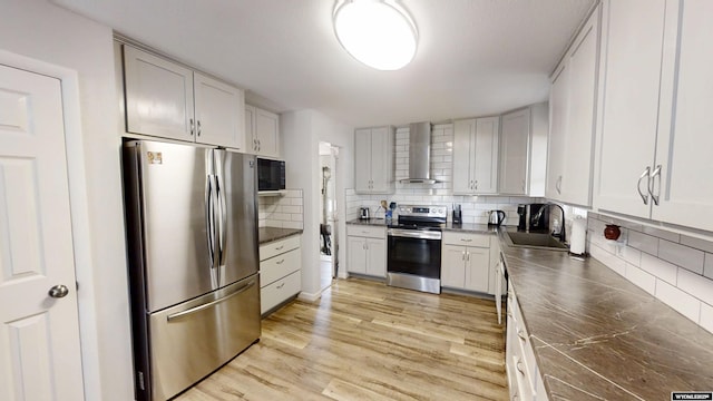 205 Daffodil, Casper, WY 82604 - kitchen with stainless steel appliances, wall chimney range hood, a sink, tasteful backsplash, and light wood-type flooring