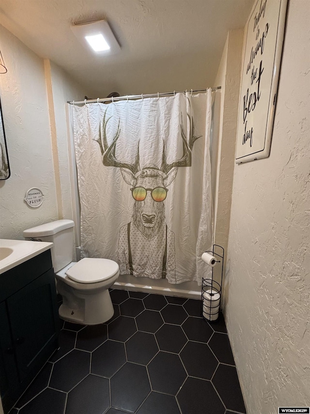 1595 S Riverbend Dr, Green River, WY 82935 - bathroom featuring a textured wall, toilet, vanity, curtained shower, and tile patterned flooring