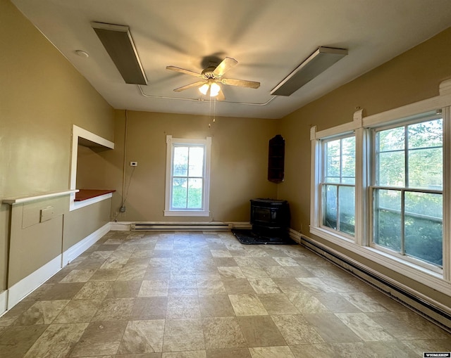 596 Garfield St, Lander, WY 82520 - unfurnished living room with a baseboard radiator, a wood stove, a ceiling fan, baseboards, and stone finish flooring