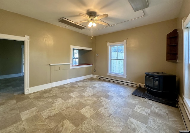 596 Garfield St, Lander, WY 82520 - empty room with a baseboard radiator, ceiling fan, stone finish floors, baseboard heating, and a wood stove