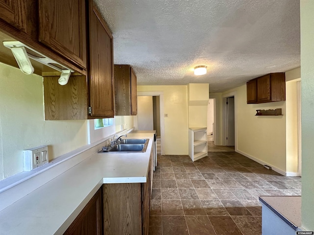 596 Garfield St, Lander, WY 82520 - kitchen featuring a sink, a textured ceiling, baseboards, dark stone finish flooring, and light countertops