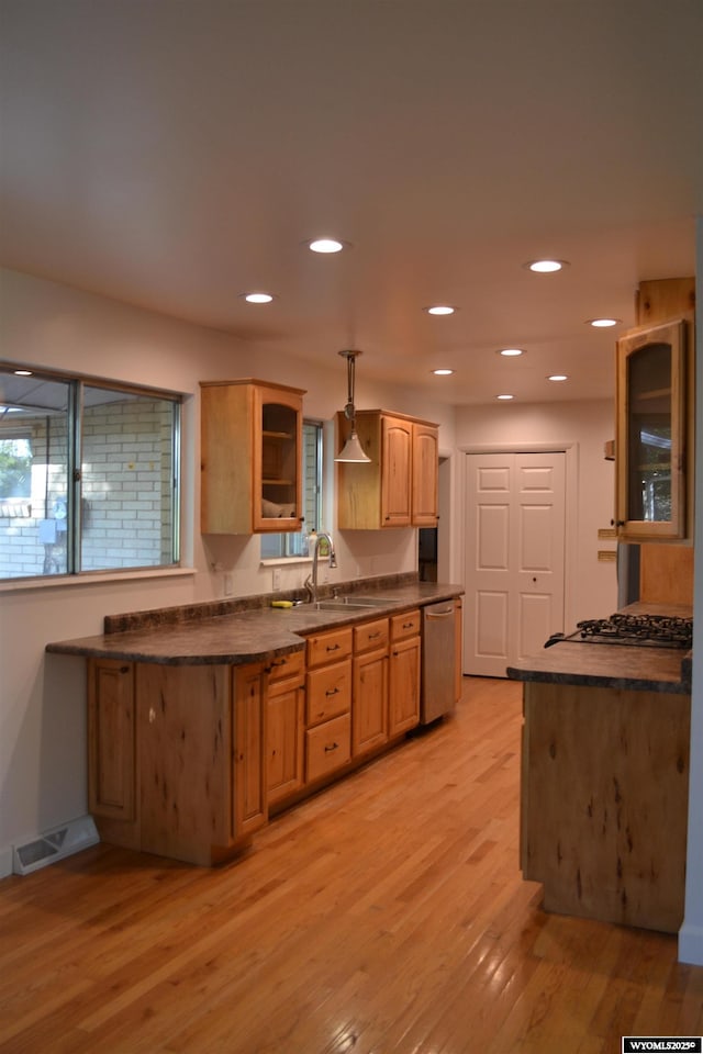 104 First St, Mountain View, WY 82939 - kitchen with stainless steel dishwasher, dark countertops, glass insert cabinets, light wood finished floors, and gas stovetop