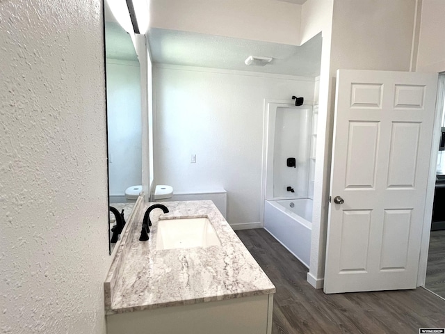 1137 Main St, Evanston, WY 82930 - bathroom with vanity, a textured wall, wood finished floors, washtub / shower combination, and toilet