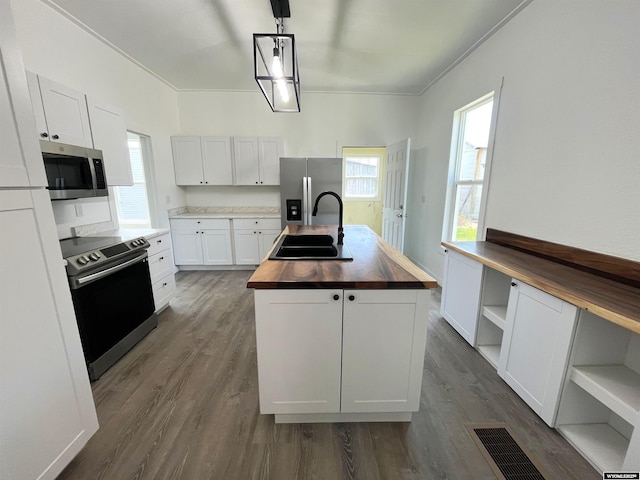 1137 Main St, Evanston, WY 82930 - kitchen featuring wooden counters, stainless steel appliances, a sink, a center island with sink, and open shelves