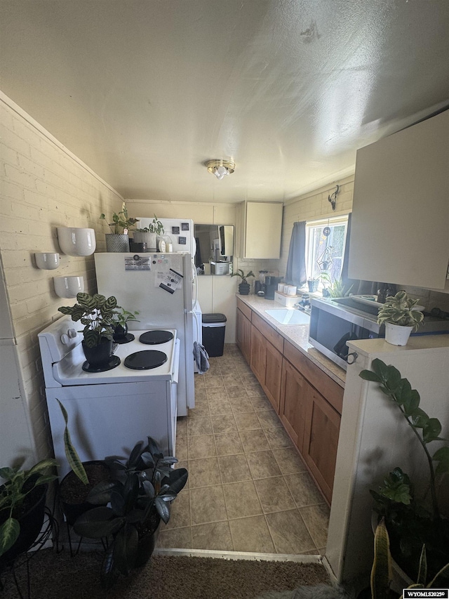 1137 Main St, Evanston, WY 82930 - kitchen with electric range, stainless steel microwave, a sink, brown cabinetry, and light countertops