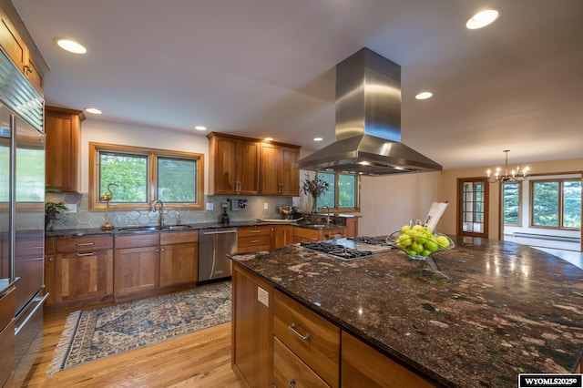 370 Aster, Casper, WY 82604 - kitchen featuring appliances with stainless steel finishes, island exhaust hood, a sink, brown cabinetry, and a chandelier