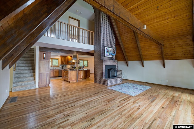 370 Aster, Casper, WY 82604 - unfurnished living room with light wood-type flooring, stairs, a brick fireplace, high vaulted ceiling, and wooden ceiling with exposed beams