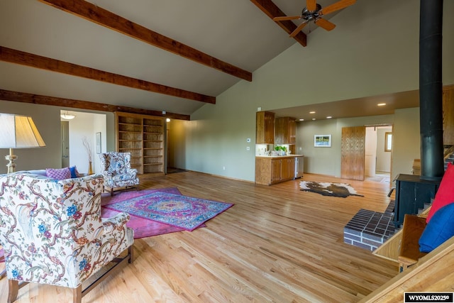 370 Aster, Casper, WY 82604 - living room featuring a wood stove, a ceiling fan, beamed ceiling, light wood-style flooring, and high vaulted ceiling