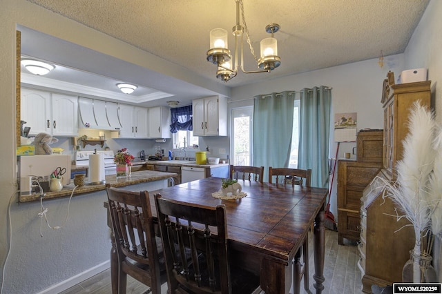 363 Oleander St, Casper, WY 82604 - dining area featuring wood finished floors, a textured ceiling, a chandelier, baseboards, and a tray ceiling