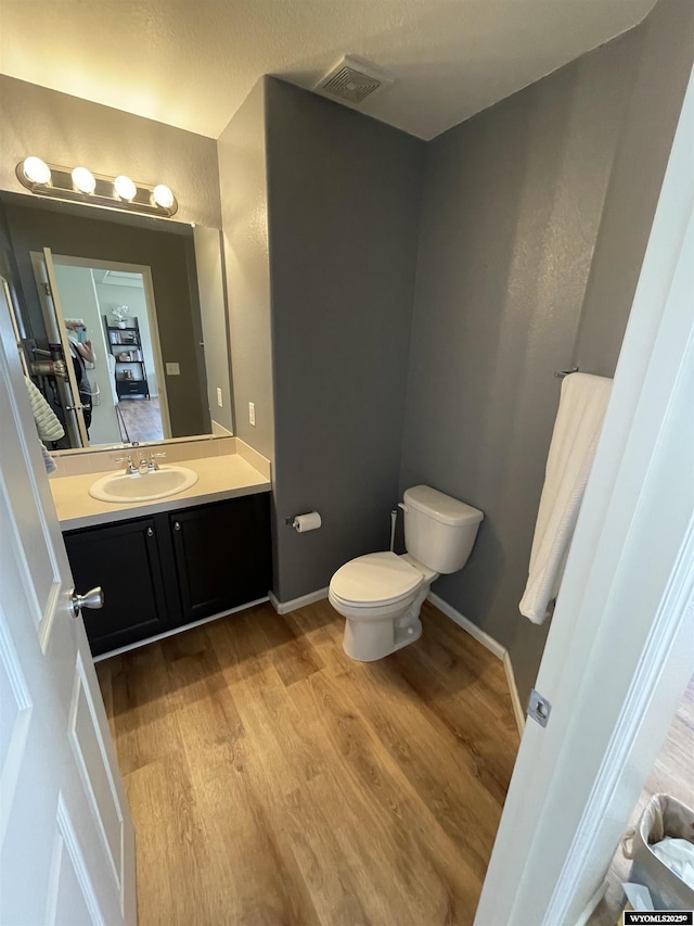 344 Via Assisi Dr, Rock Springs, WY 82901 - half bathroom featuring toilet, vanity, wood finished floors, and baseboards