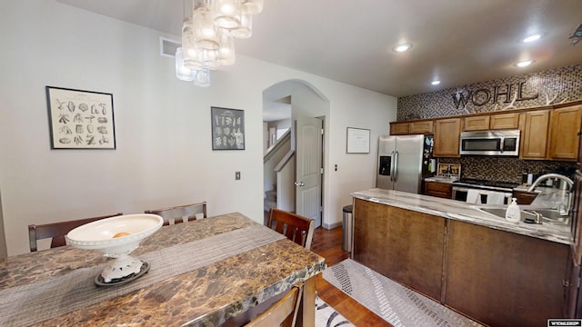 810 S 3rd Ave, Mills, WY 82604 - kitchen featuring stainless steel appliances, arched walkways, a sink, brown cabinetry, and dark wood-style flooring