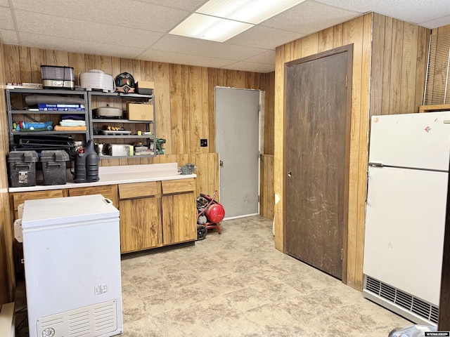 1130 Canyon Rd, Kemmerer, WY 83101 - kitchen with freestanding refrigerator, white fridge, wooden walls, light countertops, and brown cabinets