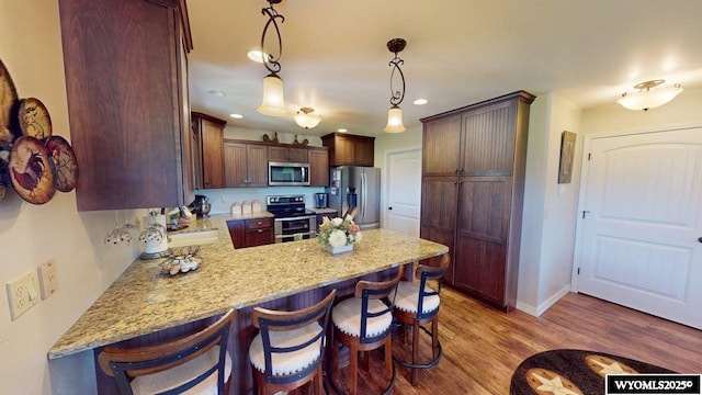 200 Irwin Ln, Lander, WY 82520 - kitchen with stainless steel appliances, a peninsula, light wood-style flooring, recessed lighting, and a kitchen breakfast bar