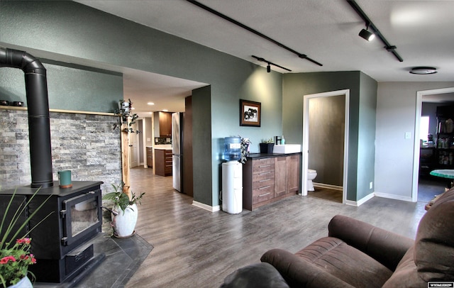 6653 Natrona Rd, Natrona, WY 82646 - living room featuring rail lighting, a wood stove, wood finished floors, and baseboards