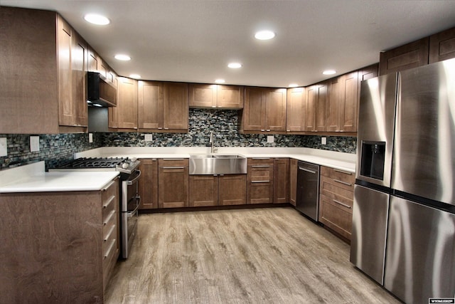 6653 Natrona Rd, Natrona, WY 82646 - kitchen featuring appliances with stainless steel finishes, a sink, light wood-style flooring, decorative backsplash, and light countertops