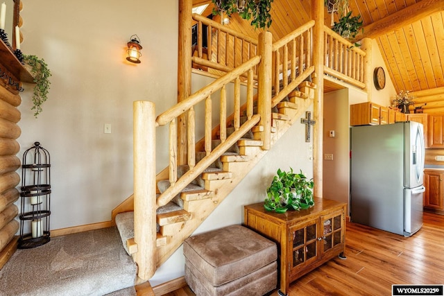 49 Cheyenne Rd, Banner, WY 82832 - staircase featuring wood ceiling with exposed beams, wood finished floors, log walls, high vaulted ceiling, and baseboards