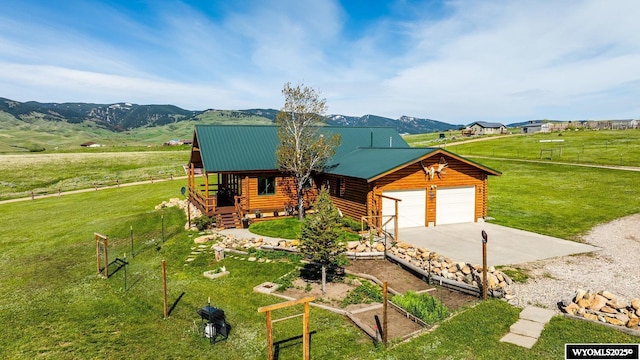 49 Cheyenne Rd, Banner, WY 82832 - cabin with concrete driveway, a mountain view, an attached garage, log exterior, and metal roof
