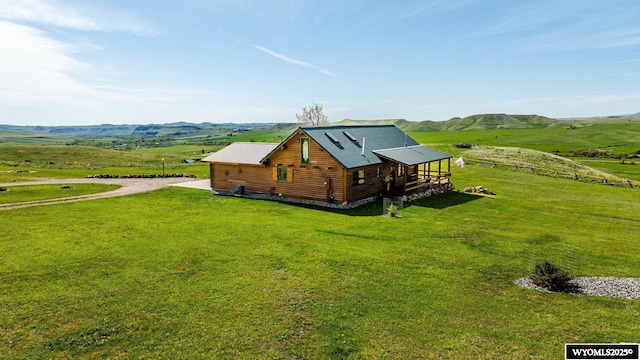 49 Cheyenne Rd, Banner, WY 82832 - view of side of home featuring driveway, a lawn, a mountain view, a rural view, and faux log siding