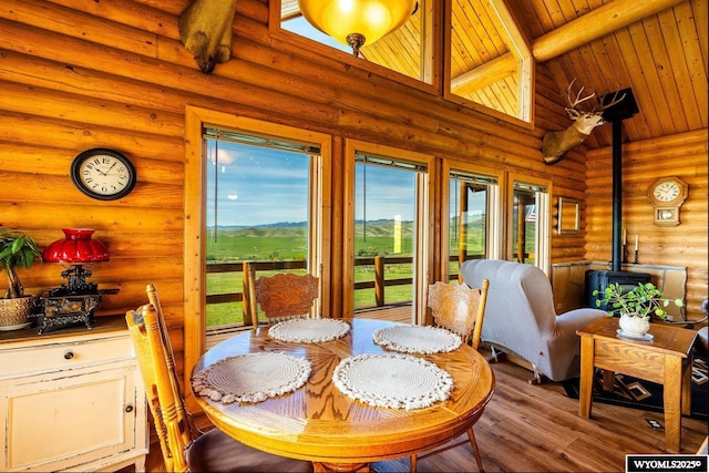 49 Cheyenne Rd, Banner, WY 82832 - dining area with a wood stove, wood finished floors, rustic walls, wooden ceiling with exposed beams, and healthy amount of natural light