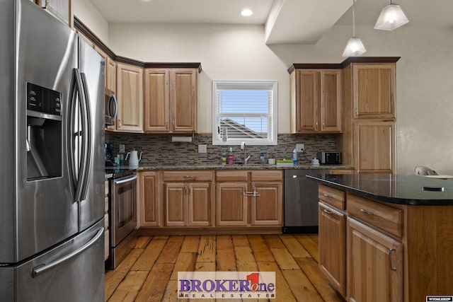 2511 Mercy Ln, Casper, WY 82609 - kitchen with stainless steel appliances, a sink, light wood-type flooring, decorative backsplash, and dark stone countertops