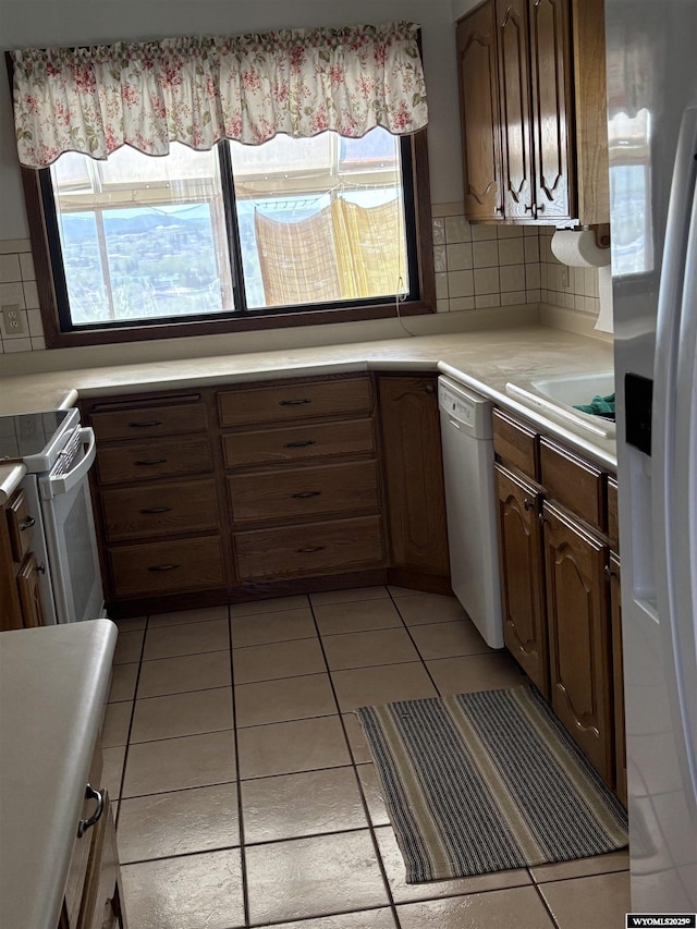 221 Rimrock Dr, Evanston, WY 82930 - kitchen with white appliances, light countertops, decorative backsplash, a sink, and light tile patterned floors