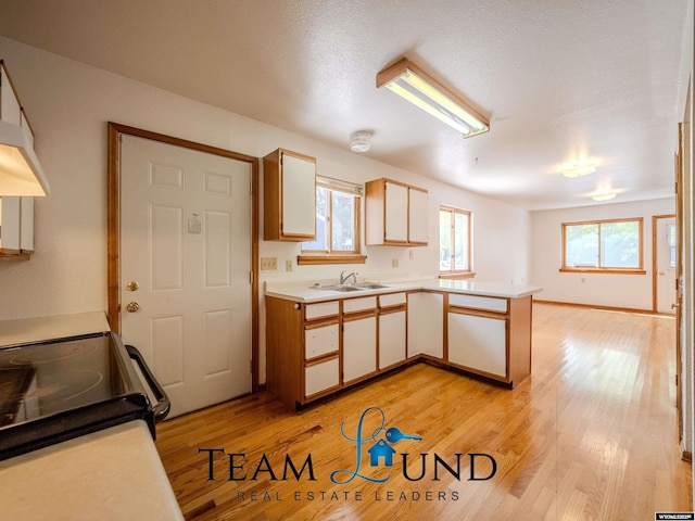 1235 S Durbin St, Casper, WY 82601 - kitchen featuring a sink, a peninsula, light countertops, light wood-style flooring, and black / electric stove