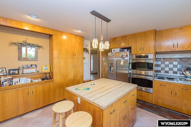 1823 Walnut St, Rock Springs, WY 82901 - kitchen featuring stainless steel appliances, under cabinet range hood, light tile patterned floors, backsplash, and a center island