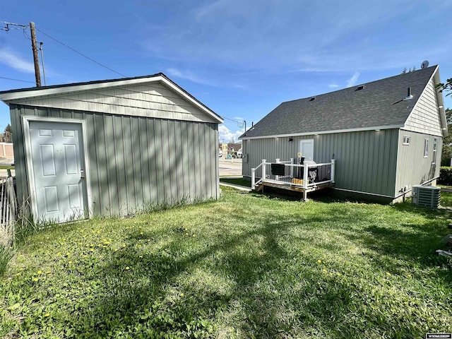 1023Pine Ave, Kemmerer, WY 83101 - back of house featuring a wooden deck, a lawn, central air condition unit, an outdoor structure, and roof with shingles