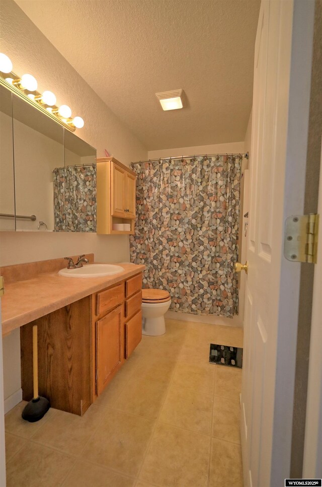 925 Skyline Dr, Douglas, WY 82633 - bathroom featuring tile patterned flooring, vanity, toilet, a textured ceiling, and a shower with shower curtain
