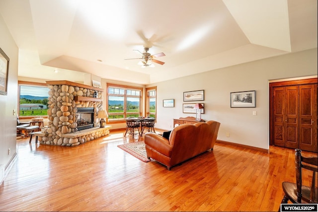 22 Pleasant Valley Ln, Sheridan, WY 82801 - living area featuring a ceiling fan, a stone fireplace, light wood finished floors, a raised ceiling, and baseboards