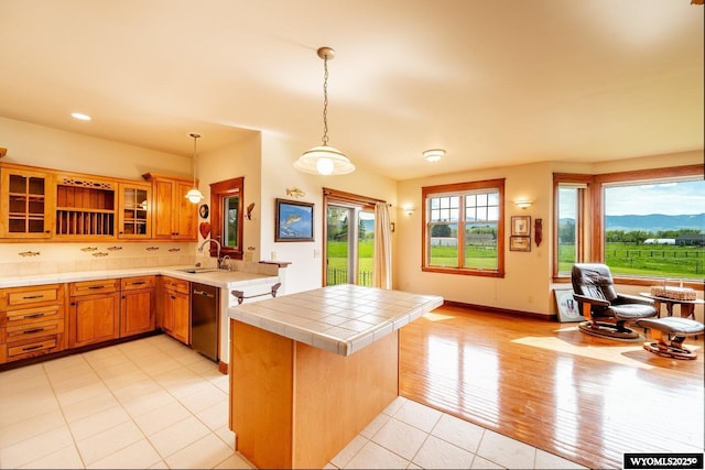 22 Pleasant Valley Ln, Sheridan, WY 82801 - kitchen with a peninsula, tile countertops, brown cabinets, glass insert cabinets, and light tile patterned floors