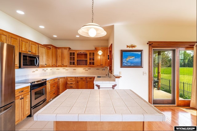 22 Pleasant Valley Ln, Sheridan, WY 82801 - kitchen featuring stainless steel appliances, brown cabinets, decorative light fixtures, glass insert cabinets, and a sink
