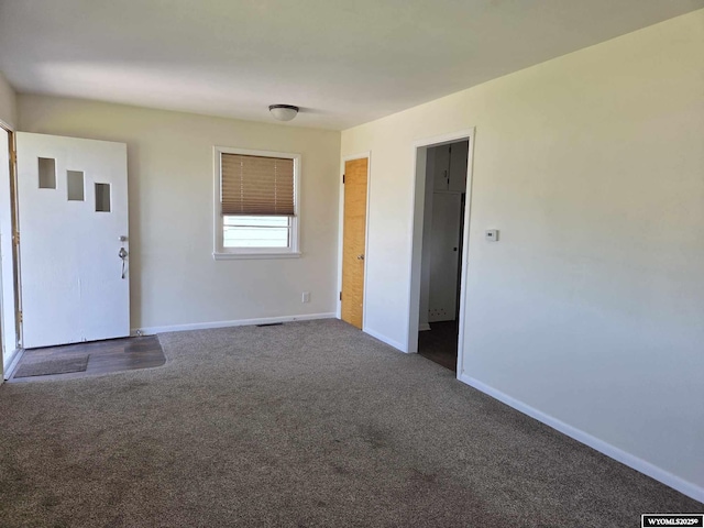 1308 Howell, Worland, WY 82401 - unfurnished living room featuring dark colored carpet and baseboards