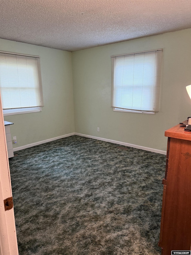 83 Calvert Ave, Hanna, WY 82327 - spare room featuring dark colored carpet, a textured ceiling, and baseboards