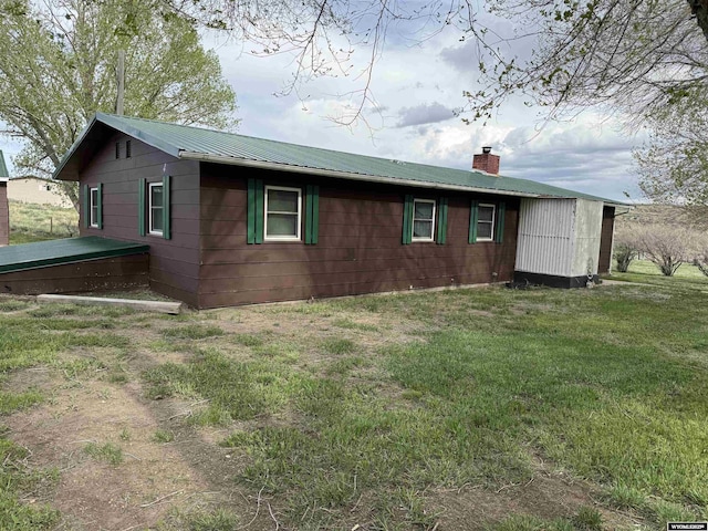 83 Calvert Ave, Hanna, WY 82327 - view of side of property featuring a chimney, metal roof, and a lawn