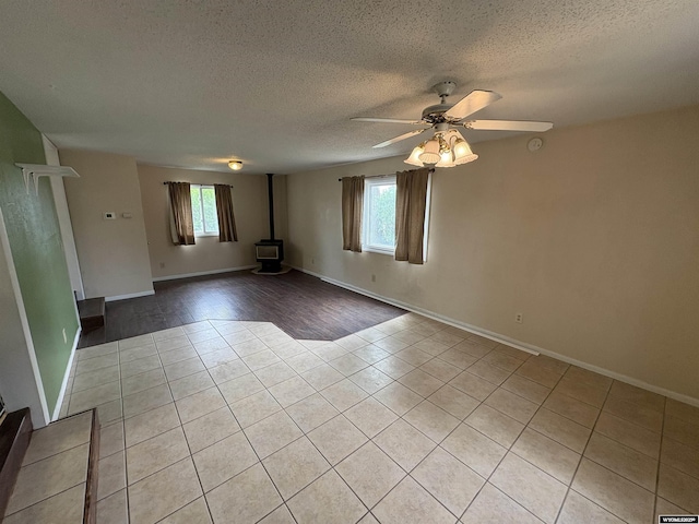 420 S 6th St, Riverton, WY 82501 - empty room featuring light tile patterned floors, plenty of natural light, a textured ceiling, a wood stove, and a ceiling fan