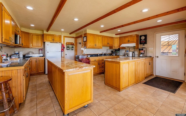 30 Nielsen Trl, Cody, WY 82414 - kitchen featuring a center island, under cabinet range hood, freestanding refrigerator, beam ceiling, and recessed lighting