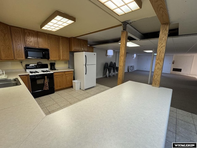 402 S 7th St E, Riverton, WY 82501 - kitchen with gas range oven, black microwave, freestanding refrigerator, a sink, and brown cabinetry