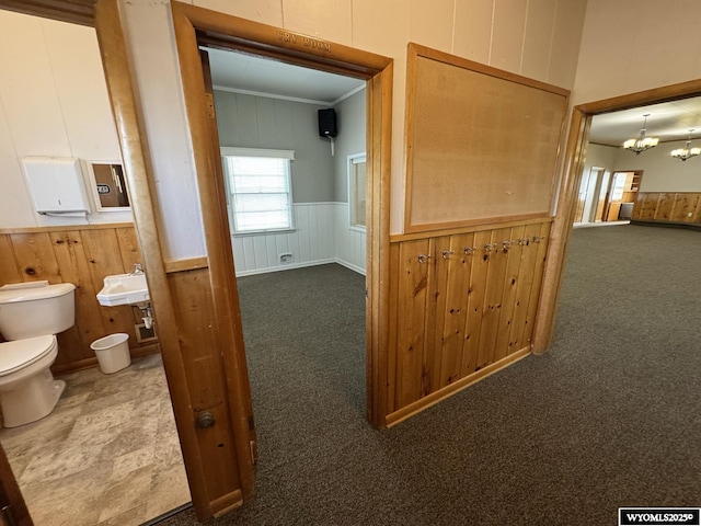 402 S 7th St E, Riverton, WY 82501 - corridor featuring carpet, a chandelier, wainscoting, crown molding, and wooden walls