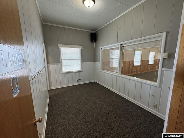 402 S 7th St E, Riverton, WY 82501 - empty room with ornamental molding, dark carpet, wooden walls, and wainscoting