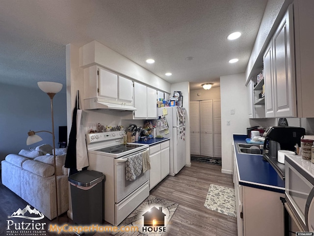 4500 S Poplar A St, Casper, WY 82604 - kitchen featuring white appliances, under cabinet range hood, a textured ceiling, white cabinetry, and recessed lighting