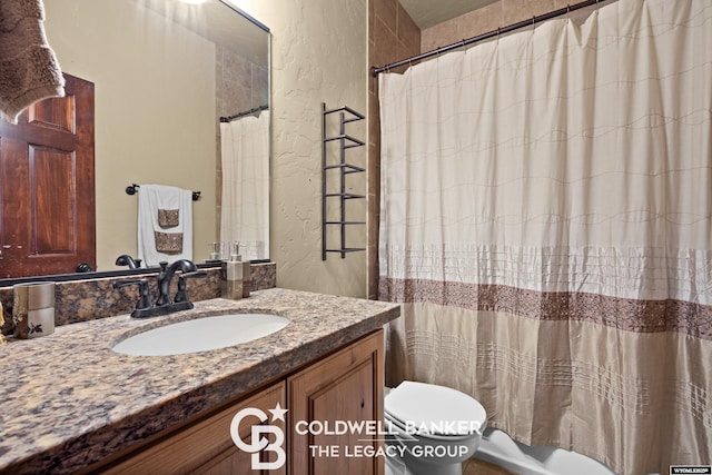 972 Cornwall St, Casper, WY 82609 - full bathroom featuring a textured wall, toilet, vanity, and a shower with shower curtain