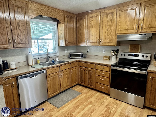 3024 Hamilton Way, Casper, WY 82609 - kitchen with stainless steel appliances, under cabinet range hood, a sink, light wood-style floors, and brown cabinetry