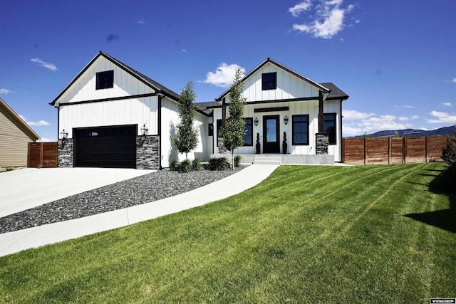 3685 Timber Wolf Ct, Casper, WY 82604 - modern inspired farmhouse featuring board and batten siding, a porch, concrete driveway, stone siding, and a mountain view
