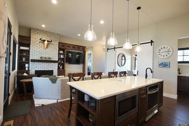 3685 Timber Wolf Ct, Casper, WY 82604 - kitchen featuring a barn door, a kitchen bar, stainless steel microwave, open shelves, and dark wood-type flooring